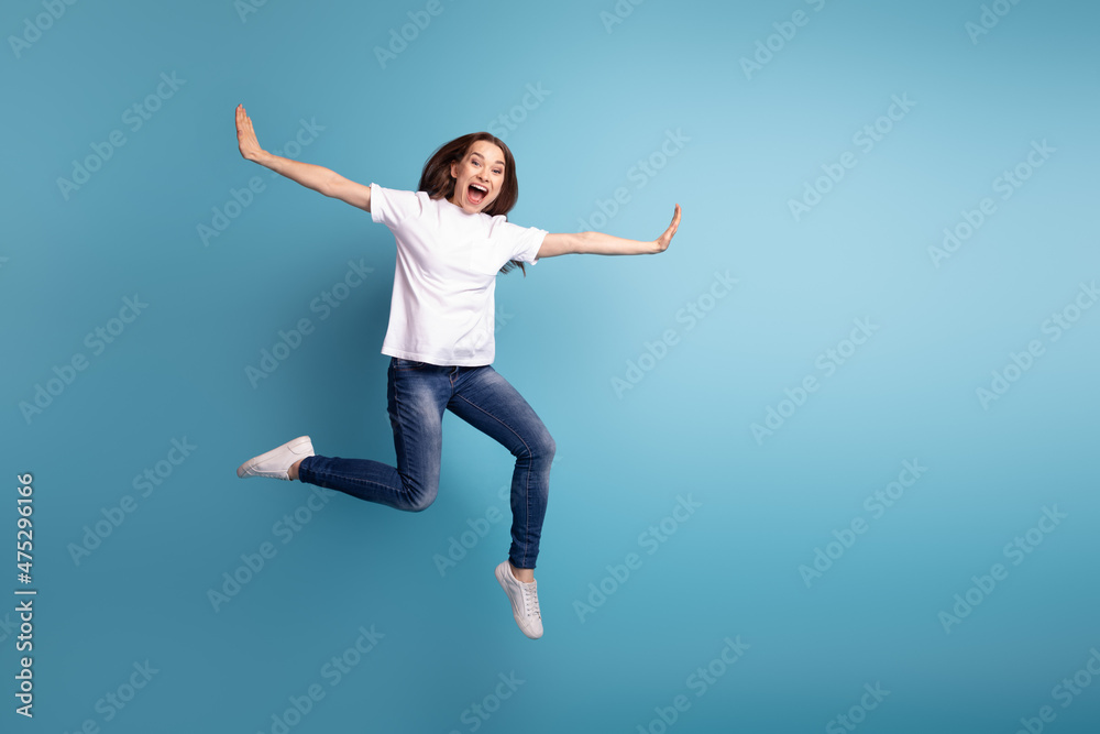 Full size photo of young pretty girl enjoy fly arms wings dreamy wear casual clothes isolated over blue color background