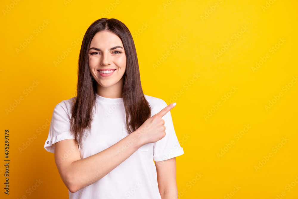 Photo of young pretty girl indicate finger empty space promotion advertise isolated over yellow color background Photo of young pretty girl indicate finger empty space promotion advertise isolated over yellow color background
