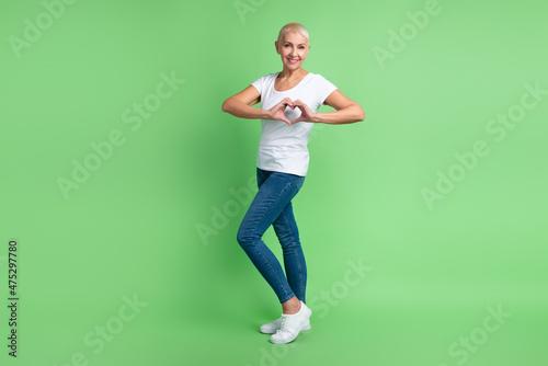 Full body profile side photo of lovely aged woman show fingers heart symbol cupid cardiac isolated over green color background © Tetiana