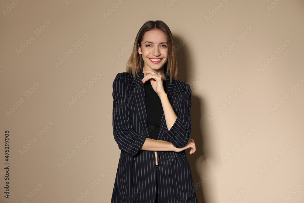 Portrait of beautiful young woman in fashionable suit on beige background. Business attire