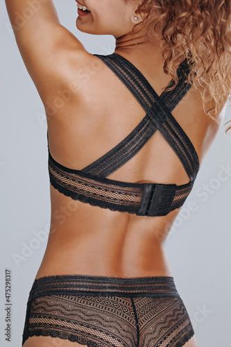 Pretty girl in black lace lingerie on a gray background back shot