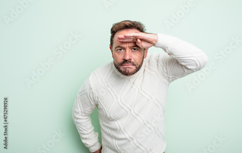 middle age handsome man looking bewildered and astonished, with hand over forehead looking far away, watching or searching