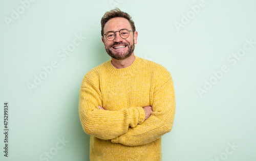 middle age handsome man looking like a happy, proud and satisfied achiever smiling with arms crossed photo