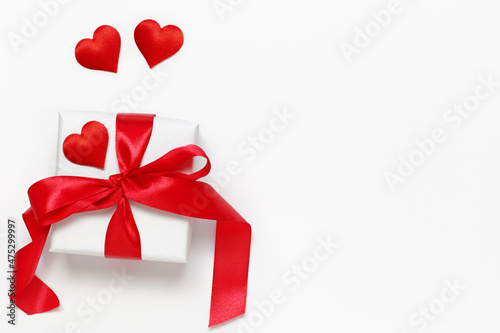 A white gift box tied with a red ribbon with hearts for Valentine's Day, Birthday, Mother's Day or International Women's Day.