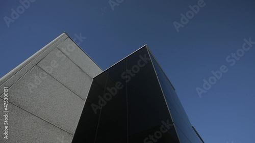 Exterior of a modern building. Sun reflecting on it. Tilt up rotating shot.