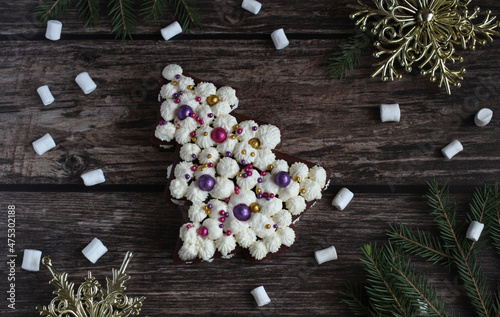 festive beautiful cake in the form of a spruce on a wooden background with marshmallows and spruce branches