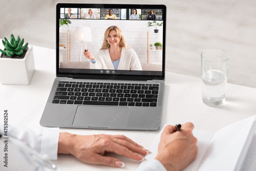 Young business lady having online group conference with her work colleagues on laptop from home office