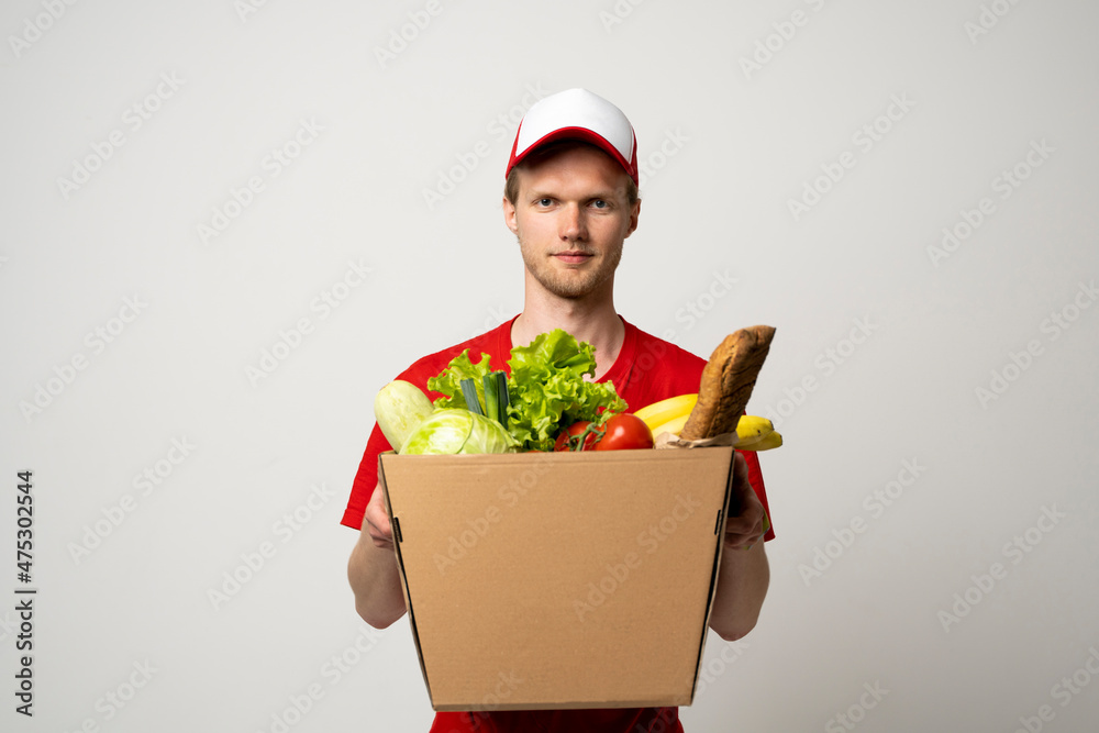 Grocery store delivery man wearing an red t-shirt delivering food to a customer at home. Food delivery service. Grocery store delivery man wearing an red t-shirt delivering food to a customer at home. Food delivery service.