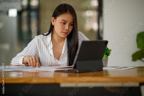Smiling Young business woman working on a laptop computer in a modern office,doing finances, accounting analysis, report data pointing graph Freelance education and technology concept.