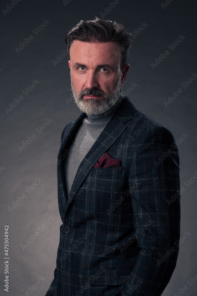 Portrait of a stylish elegant senior businessman with a beard and casual business clothes in photo studio isolated on dark background gesturing with hands Portrait of a stylish elegant senior businessman with a beard and casual business clothes in photo studio isolated on dark background gesturing with hands