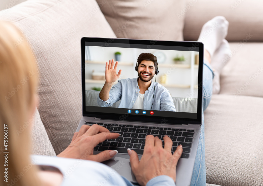 Distance communication. Young lady sitting on sofa with laptop, making video call, speaking to her boyfriend online Distance communication. Young lady sitting on sofa with laptop, making video call, speaking to her boyfriend online