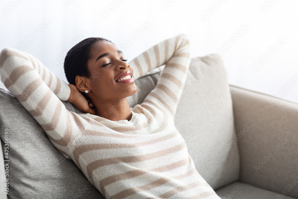 © Prostock-studio - Home Comfort. Relaxed Black Female Sitting On Couch With Closed Eyes © Prostock-studio - Home Comfort. Relaxed Black Female Sitting On Couch With Closed Eyes