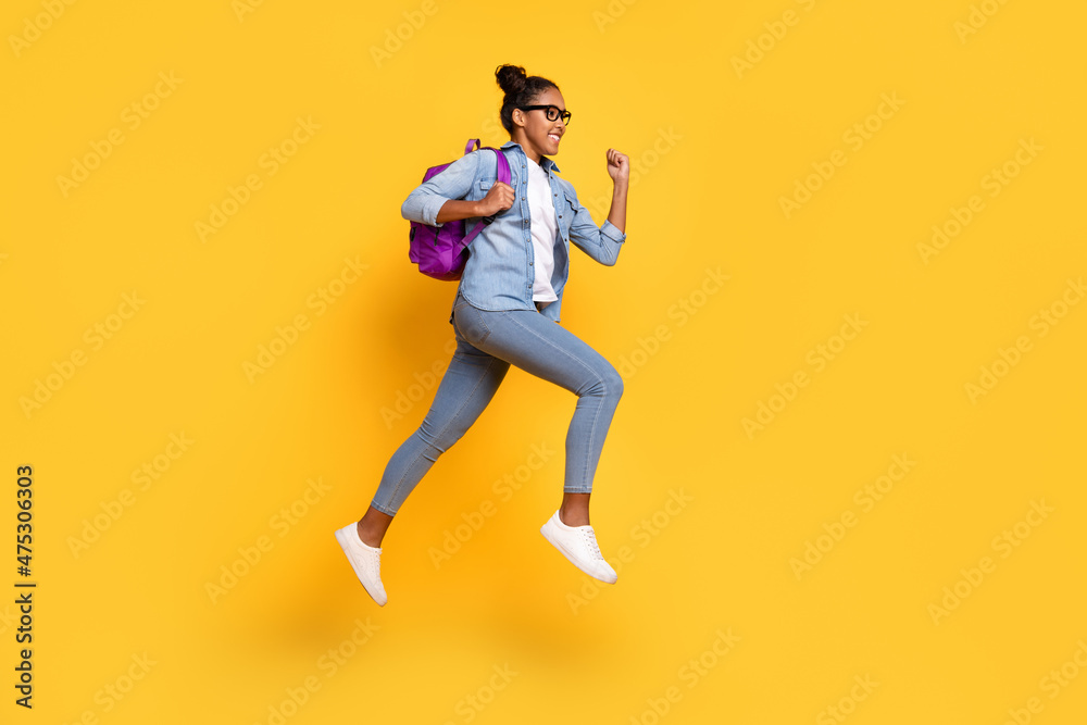 Full size profile side photo of young african girl jumper active fast run rucksak college isolated over yellow color background