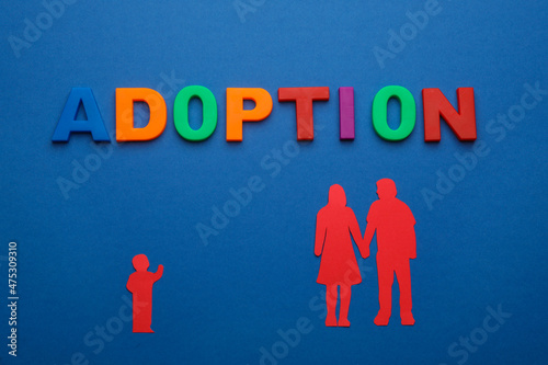 Figures of parents with child and word Adoption on blue background, flat lay photo