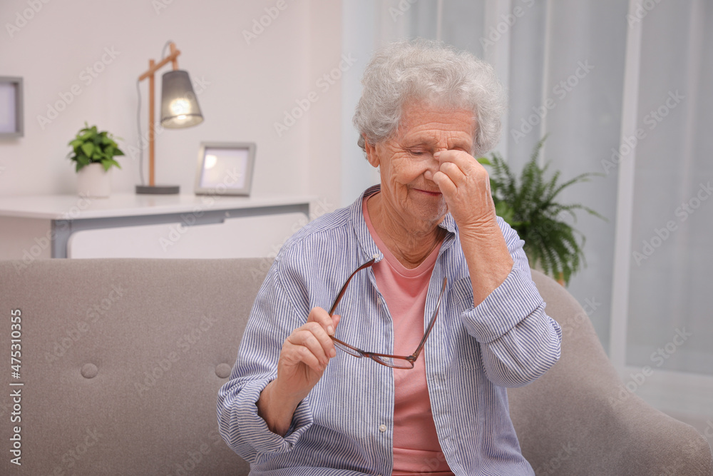 Senior woman with headache sitting on sofa at home. Space for text Senior woman with headache sitting on sofa at home. Space for text
