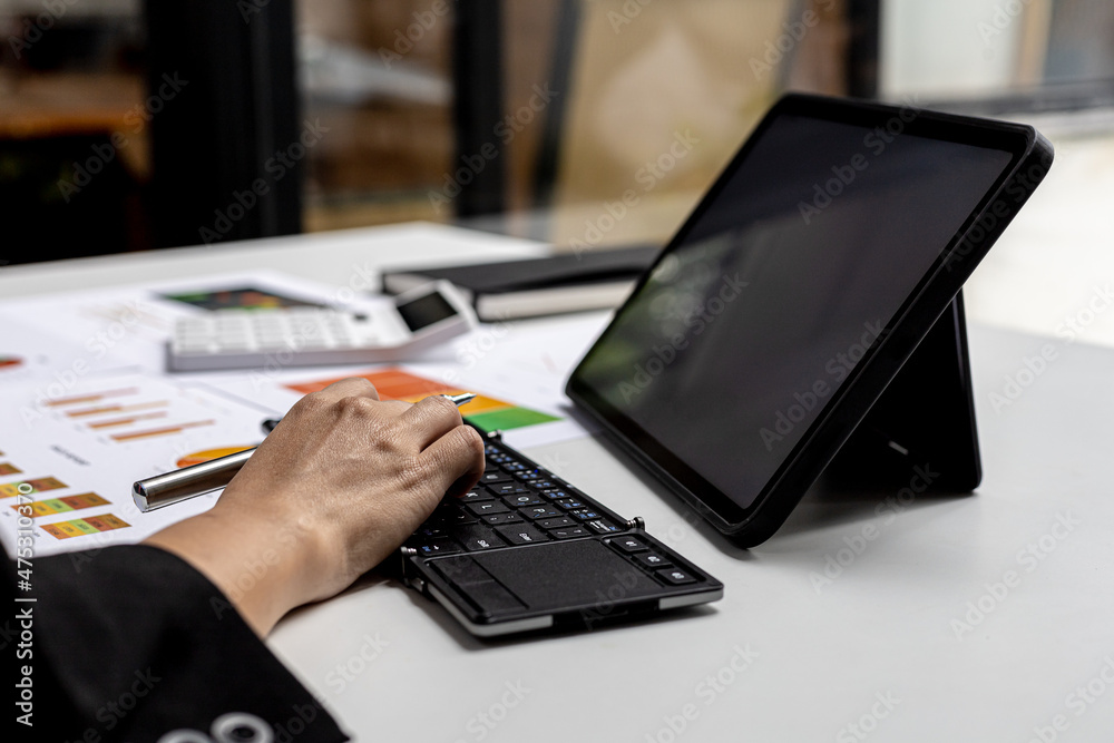 Hands of business woman typing on a tablet keyboard, she is using a messaging program to talk to a business partner who is opening a startup company. Concept of using technology in communication. Hands of business woman typing on a tablet keyboard, she is using a messaging program to talk to a business partner who is opening a startup company. Concept of using technology in communication.
