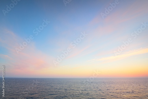 Fototapeta Naklejka Na Ścianę i Meble -  Baltic sea at sunset. Clear sky, blue and pink glowing clouds, soft golden sunlight. Water surface texture. Picturesque aerial dreamlike seascape, cloudscape, nature. Panoramic vie