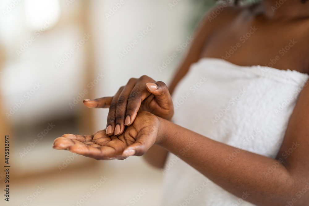Fototapeta premium Cropped view of young black woman applying moisturizing hand cream at home, closeup