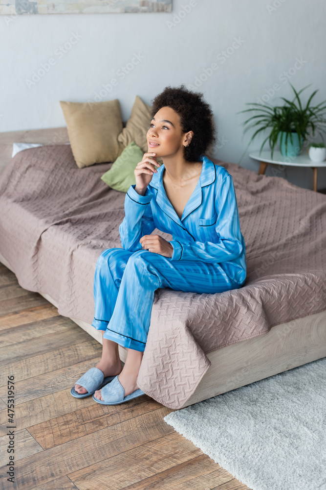Dreamy african american woman sitting on bed at home Dreamy african american woman sitting on bed at home