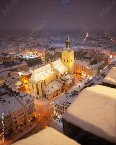Gorgeus cityscape of winter Lviv city with roofs covered by snow from top of town hall, Ukraine, Europe. Latin Cathedral glowing by city lights. Landscape photography
