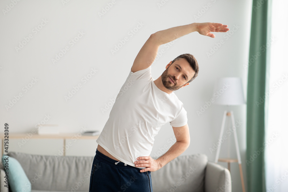 Athletic middle-aged man in sportswear exercising at home Athletic middle-aged man in sportswear exercising at home