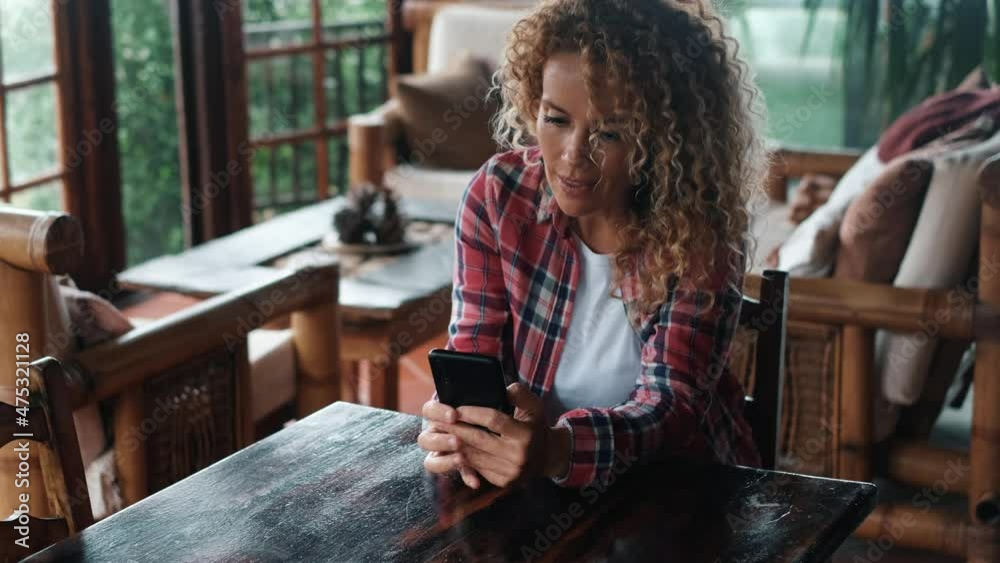 Woman at home in living room using mobile phone connection to check notification or social media accounts. Concept of female people and indoor house technology connection. Lady messaging on cellular