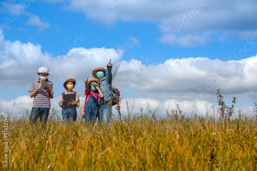 Children and mother learning and playing on grassland on blue sky background