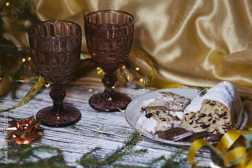 Atmospheric Christmas dinner with Christmas stollen, chocolate and two glasses. Holidays decorations. Aesthetic traditions atmosphere background photo