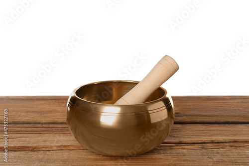 Golden singing bowl and mallet on wooden table against white background