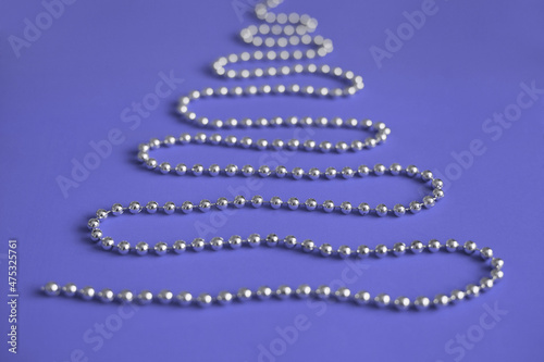 Shiny silver christmas tree beads shaped as tree on purple very peri background