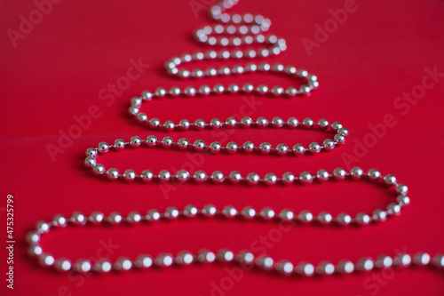 Shiny silver christmas tree beads shaped as tree on red background