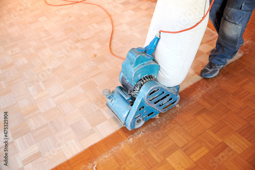 Hardwood floor restoring - Worker polishing parquet floor with grinding machine