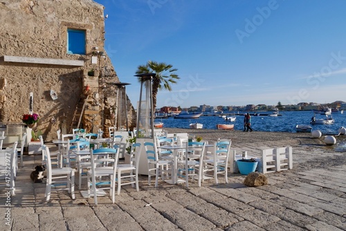 Lovely outdoor seating area with gorgeous view of the sea and fishing boats. Marzamemi, Province Syracuse, Sicily.