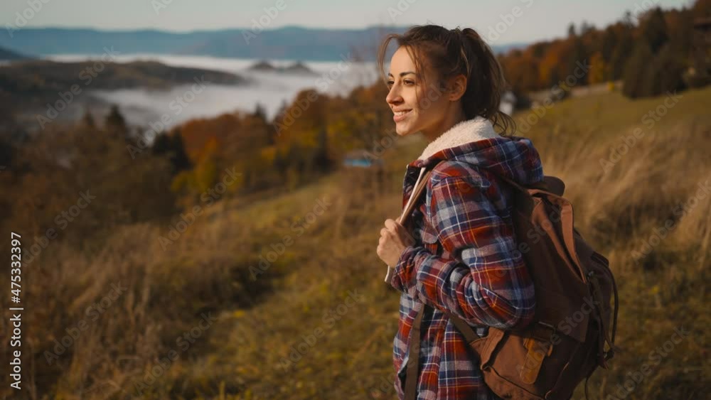 hipster millennial young woman walks on top of mountain summit at sunrise, looking ahead, enjoying beautiful view, happy and drunk on life, youth and happiness.