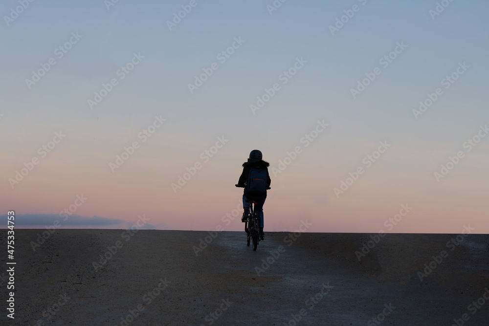 Rear view of a cyclist against the light of a beautiful sunset. Freedom concept or holiday.
