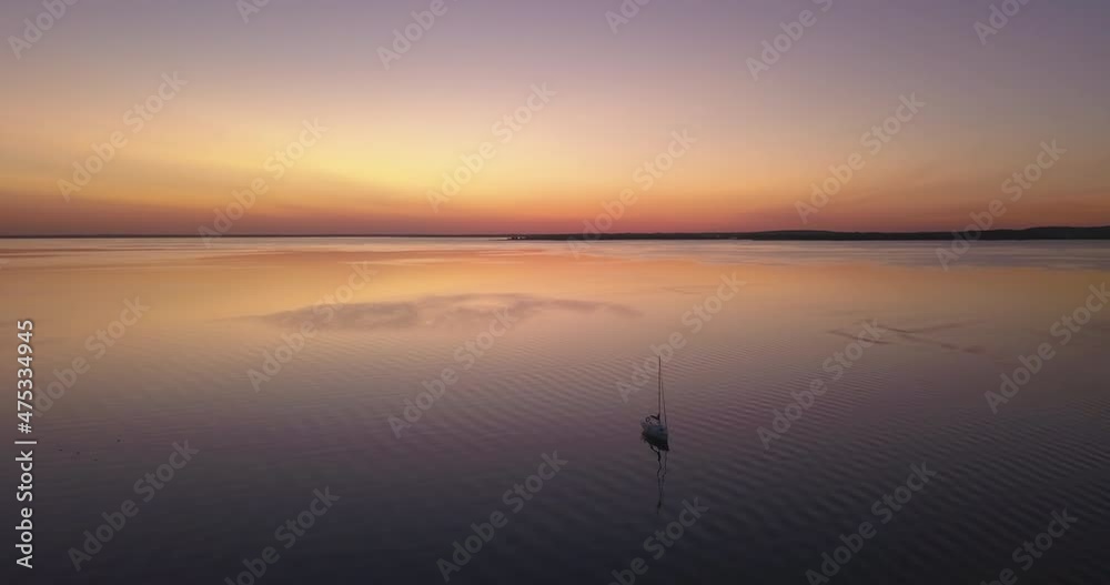 Sunset over the lake, aerial landscape. Pastel orange sky during summer sundown. Slow drone flight low over the water and sailboat. Sunset over the lake, aerial landscape. Pastel orange sky during summer sundown. Slow drone flight low over the water and sailboat.