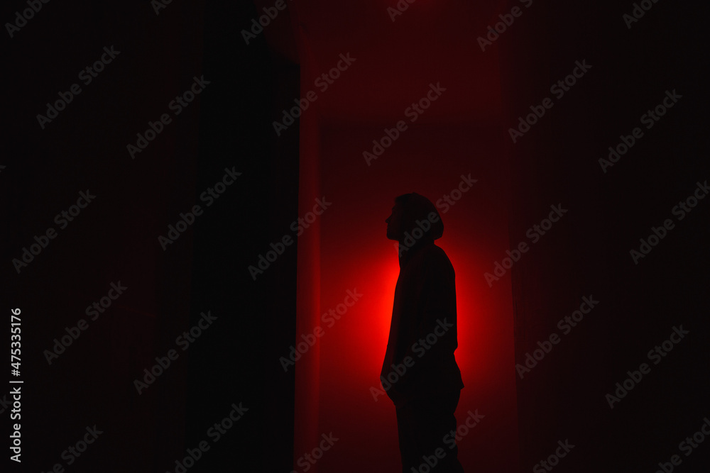 Silhouette of a man on a red background.
Silhouette of a guy in the dark.