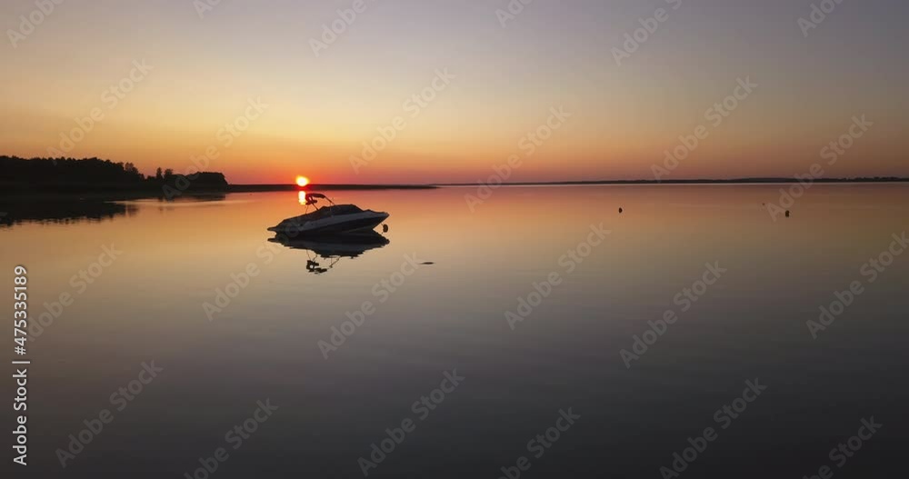 Beautiful sunset over the lake surrounded by the forest and docked motorboat. Orange sun and pastel sky during summer sundown. Slow drone flight. Beautiful sunset over the lake surrounded by the forest and docked motorboat. Orange sun and pastel sky during summer sundown. Slow drone flight.
