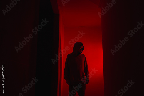 Silhouette of a man on a red background. Silhouette of a guy in the dark.