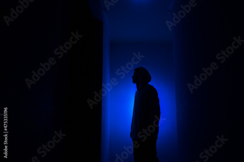 Silhouette of a guy in the dark.
Man in blue light.