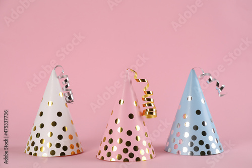 Bright party hats with streamers on pink background