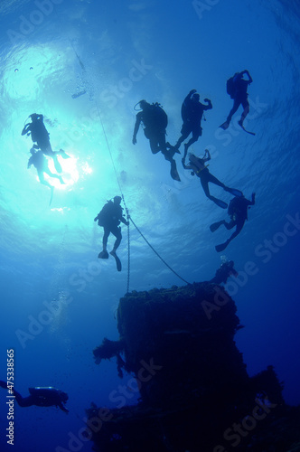 Scuba divers at mooring line on top of shipwreck.