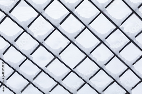 Winter background snow field. in the foreground is a geometric lattice covered with snow. Abstract background