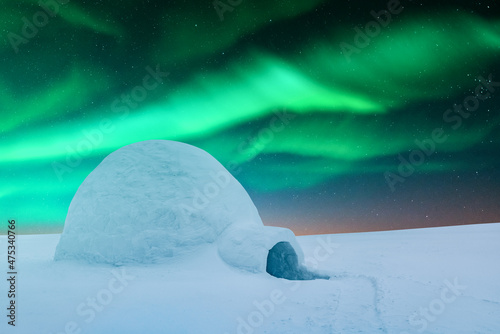Aurora borealis. Northern lights in winter mountains. Wintry scene with glowing polar lights and snowy igloo. Landscape photography © Ivan Kmit