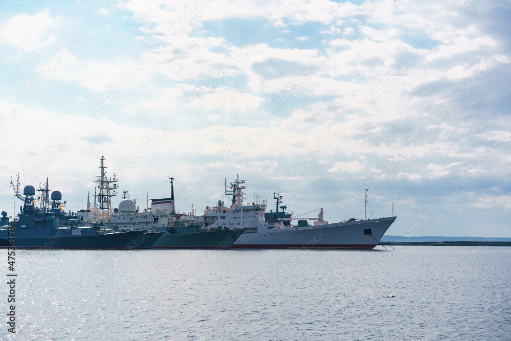 Ships of russian navy are on dock on water against background of sky with clouds. Selective focus