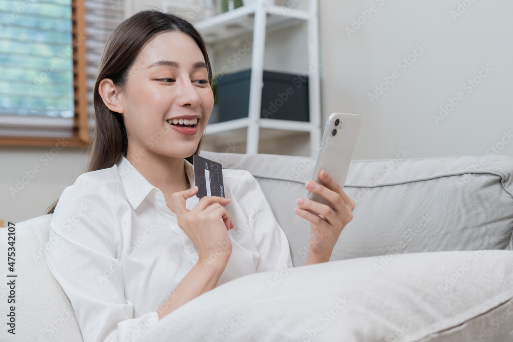 Internet banking, Online shopping at home, happy asian young woman, girl hand in holding credit card, using smartphone, mobile spending money with purchase, pay on store at home. Shopaholic e-commerce Internet banking, Online shopping at home, happy asian young woman, girl hand in holding credit card, using smartphone, mobile spending money with purchase, pay on store at home. Shopaholic e-commerce