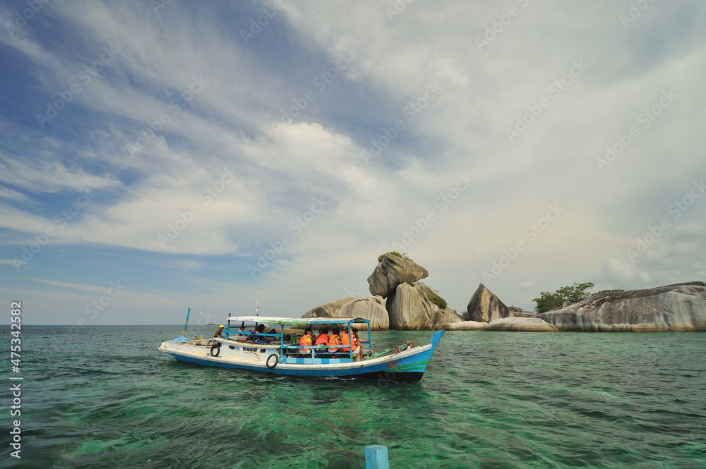 Tourist boats with full of passengers cruising near unique rock formation island in Belitung, Indonesia. 