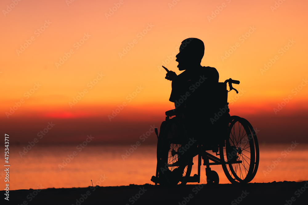 Behind of young man with disability looking sunset on the sea beach at summer, Positive photos give life energy and power concept.