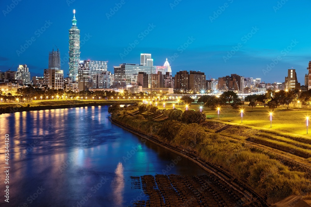 Obraz premium Night view of Taipei City by riverside with skyscrapers and beautiful reflections on smooth water ~ Landmarks of Taipei 101 Tower, Keelung River, Xinyi District and downtown area at dusk
