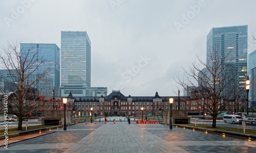 Morning scenery of the majestic historical building of Tokyo Train Station among modern office towers with a pedestrian promenade in the foreground under moody cloudy sky in Chiyoda, Tokyo, Japan